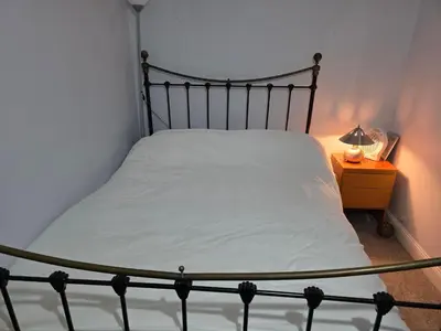 a bed in a bedroom with a lamp on a night stand at Guest Room in Colchester Hythe in Colchester