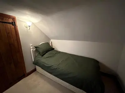 a small bedroom with a bed with a green pillow at Beautiful Cottage opposite Hedingham Castle! in Castle Hedingham