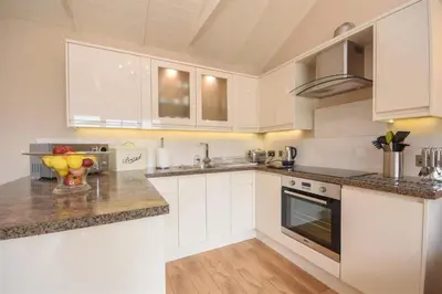 a kitchen with white cabinets and granite counter tops at The Barn in Little Maplestead