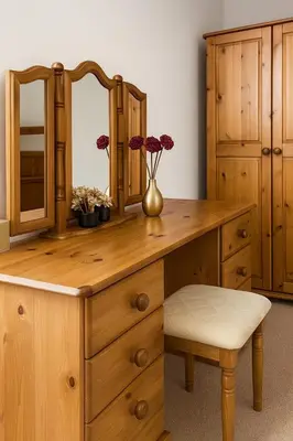 a wooden dressing table with a mirror and a vase with flowers at The Little Nest in Colchester in Colchester