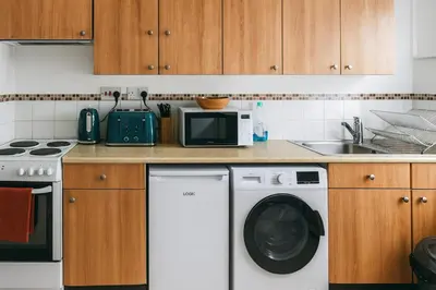 a kitchen with a washing machine and a microwave at The Little Nest in Colchester in Colchester