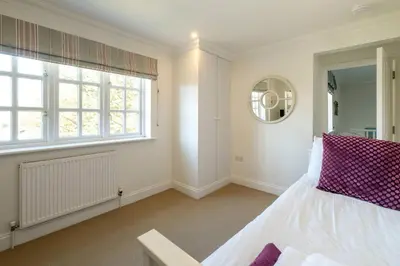 a bedroom with a bed and a window and a mirror at 7 Sanctuary Court - sleeps 12 - Thorpeness - Aldeburgh Coastal Cottages - Close to the Beach, Golf and the Country Club in Thorpeness