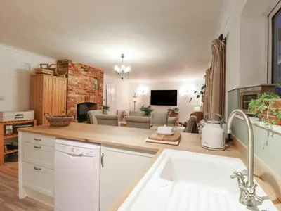 a kitchen with a sink and a living room at Berkley Cottage in Colchester