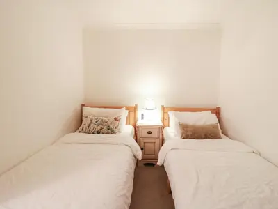 two twin beds in a room with a night stand at Berkley Cottage in Colchester