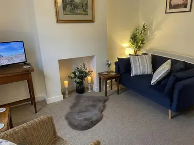 a living room with a blue couch and a tv at Charming Willow Cottage in historic Grantchester in Barton