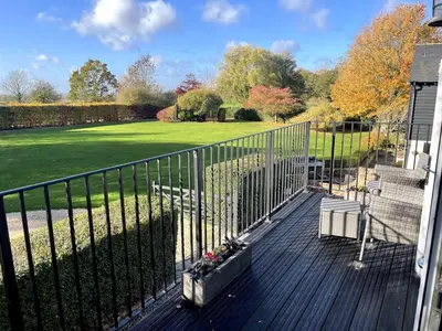 a porch with a fence and a lawn at Greenfinch Lodge