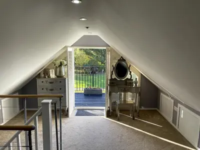an attic hallway with a staircase leading to a door at Greenfinch Lodge
