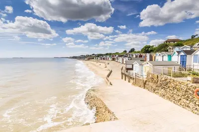 a beach with a row of houses and the ocean at Spacious 8 Berth Caravan With Decking At Naze Marine In Essex Ref 17012Rd in Walton-on-the-Naze