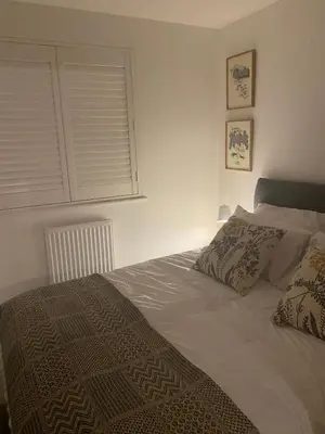 a bedroom with a bed with a blanket and a window at The Pink House in Lavenham