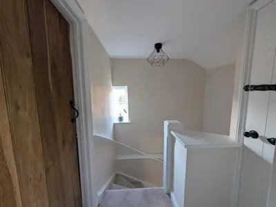 a room with a staircase with a white refrigerator at Central Grade 2 listed cottage in Attleborough