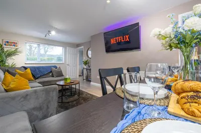 a living room with a couch and a table at Modern Comfort, Free Parking, Netflix & Disney plus in every Bedroom and Living Room in Shephall