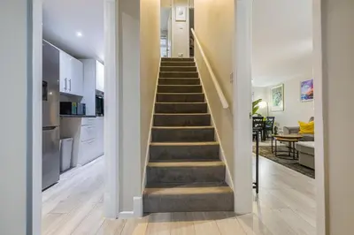 a staircase leading up to a kitchen and a living room at Modern Comfort, Free Parking, Netflix & Disney plus in every Bedroom and Living Room in Shephall