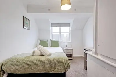 a white bedroom with a bed with green pillows at Surehaven Stays 6 Bedroom House Great for Teams in Colchester