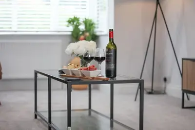 a table with a bottle of wine and wine glasses at Surehaven Stays 3 Bedroom House Braintree in Braintree