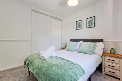 a bedroom with a large white bed and a night stand at Surehaven Stays 3 Bedroom House Braintree in Great Notley