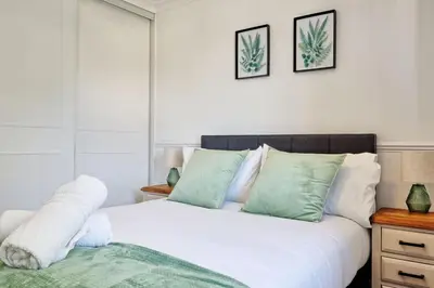 a bedroom with a bed with green and white pillows at Surehaven Stays 3 Bedroom House Braintree in Great Notley