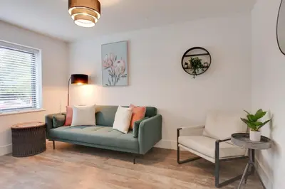 a living room with a green couch and a chair at Surehaven Stays 4 Bedroom House Braintree in Braintree