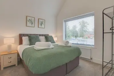 a bedroom with a bed with green sheets and a window at Surehaven Stays 4 Bedroom House Braintree in Braintree
