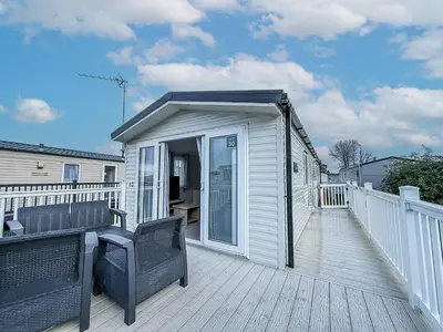 a covered deck with a chair on a house at Lovely 8 Berth Caravan With Decking To Hire At Naze Marine In Essex Ref 17030Ga in Walton-on-the-Naze