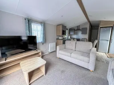 a living room with a couch and a flat screen tv at Lovely 8 Berth Caravan With Decking To Hire At Naze Marine In Essex Ref 17030Ga in Walton-on-the-Naze