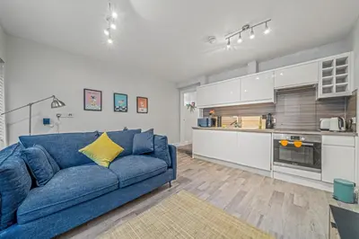 a living room with a blue couch and a kitchen at College Lane Apartment, Bury St Edmunds in Bury Saint Edmunds