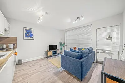a living room with a blue couch and a kitchen at College Lane Apartment, Bury St Edmunds in Bury Saint Edmunds