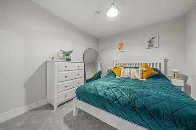 a bedroom with a bed and a white dresser at College Lane Apartment, Bury St Edmunds in Bury Saint Edmunds