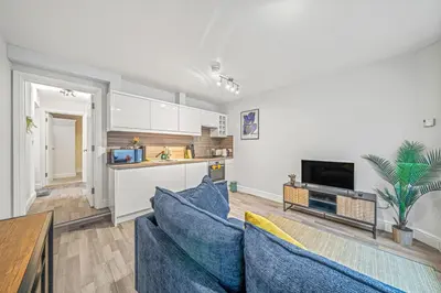 a living room with blue couches and a kitchen at College Lane Apartment, Bury St Edmunds in Bury Saint Edmunds