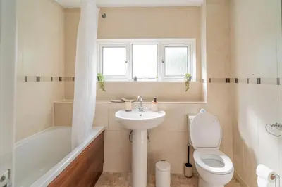 a white bathroom with a toilet and a sink at Spacious 3-Bed Home with parking in Lexden