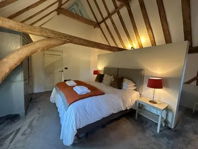 a bedroom with a large bed and a table at Scotland Hall Barn, Stoke by Nayland, Suffolk in Stoke by Nayland