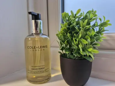 a bottle of oil next to a vase with a plant at Nr Addenbrookes Large Hot Tub Stay Sleeps 10 in Barnwell Junction Station