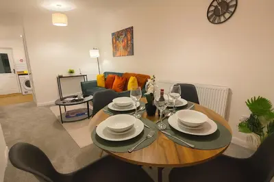 a living room with a table with plates and wine glasses at Nr Addenbrookes Large Hot Tub Stay Sleeps 10 in Barnwell Junction Station