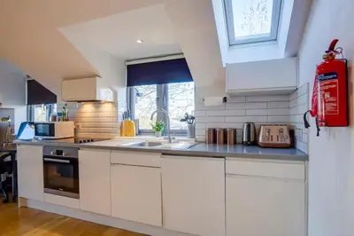 a kitchen with white cabinets and a sink at Stylish and Modern Flat with Free Parking - Pass the Keys in Cambridge
