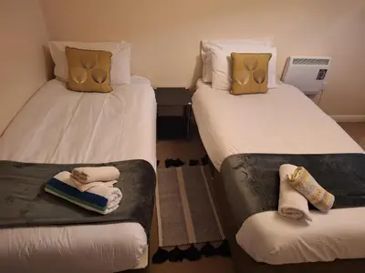 two beds in a hotel room with towels on them at 2 Bed - Sleeps 4 - Free Parking in Ely