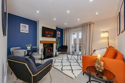 a living room with an orange couch and a fireplace at New 4BR Gem, Central, 3 Car Drive, Contractor Stay in South Benfleet