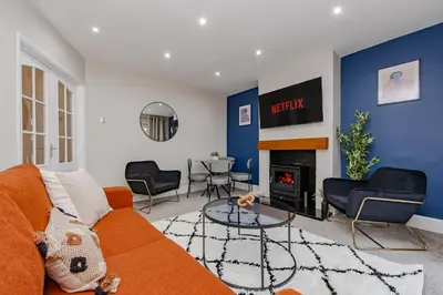 a living room with a orange couch and a fireplace at New 4BR Gem, Central, 3 Car Drive, Contractor Stay in South Benfleet