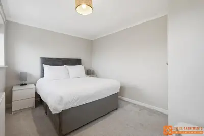 a bedroom with a large bed with white sheets at 4 Bed, 2 Bath Detached House, Parking, Fast Wifi in Colchester