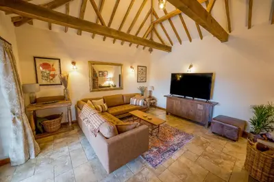 a living room with a couch and a flat screen tv at An elegant countryside hideaway with four indulgent ensuite bedrooms in Fressingfield