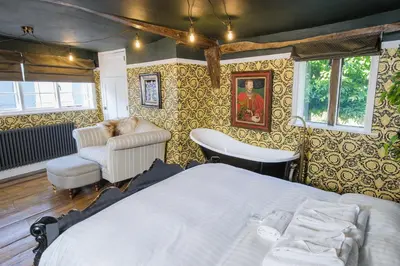 a bedroom with a bed and a chair at Luxury Rock & Roll Suite in Manor House in Saffron Walden