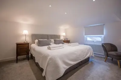 a bedroom with a large white bed and a chair at The Secret Cottage, Aldeburgh in Aldeburgh