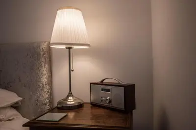 a lamp and a radio on a table next to a bed at The Secret Cottage, Aldeburgh in Aldeburgh