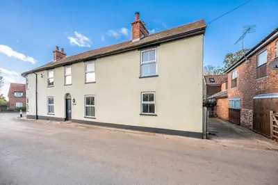a white building on the side of a street at The Knoll, Alderton in Alderton