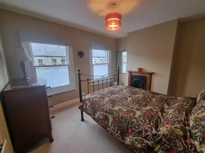 a bedroom with a bed and a fireplace and two windows at Central Cambridge -comfortable Victorian Terrace in Cambridge
