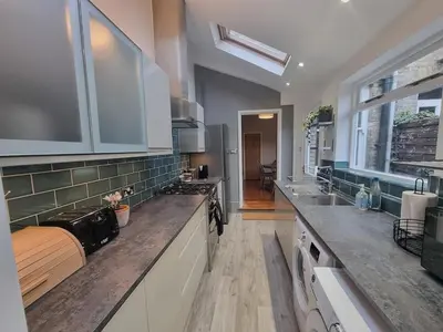 a large kitchen with white cabinets and counter tops at Central Cambridge -comfortable Victorian Terrace in Cambridge