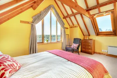 a bedroom with a bed and a chair and a window at 1 Bed in Orford oc-m34121 in Orford