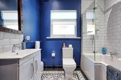 a blue bathroom with a toilet and a tub and a sink at Cosy 2 Bedroom Flat Near Westcliff On Sea Beach & Hamlet Court Road in Southend-on-Sea