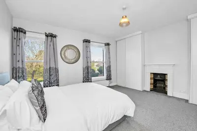 a white bedroom with a bed and a fireplace at 17 OutRisbygate St - 3 bedroom house that sleeps 6 with one private parking space in Bury Saint Edmunds
