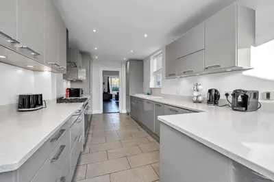 a white kitchen with white counter tops and appliances at 17 OutRisbygate St - 3 bedroom house that sleeps 6 with one private parking space in Bury Saint Edmunds