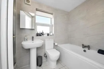 a white bathroom with a toilet and a sink at 17 OutRisbygate St - 3 bedroom house that sleeps 6 with one private parking space in Bury Saint Edmunds