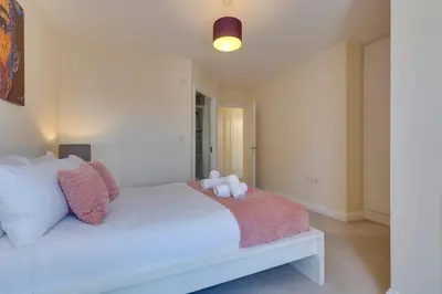 a bedroom with a white bed with pink pillows at Modern House with Free Parking & Superfast WiFi in Cambridge